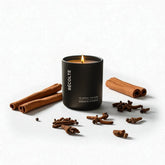 Black candle labeled 'Reçolte' with cinnamon sticks and cloves on a white background