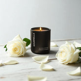Gourmella candle with white roses on a wooden surface
