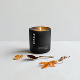 MOUSSE AND MAPLE CANDLE IN A BLACK VESSEL ON A WHITE BACKGROUND AND 2 AUTUMN LEAVES