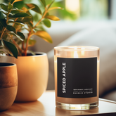 Spiced Apple candle with plantss on a wooden surface with a blurred autumn background.