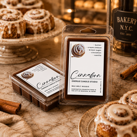Cinnamon-scented wax melts with packaging on a table with cinnamon rolls and a bakery bottle.