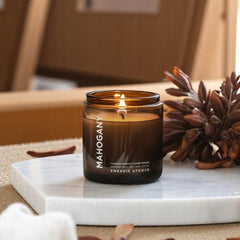 a candle sitting on a white marble slated platform with mahogany and teakwood leaf