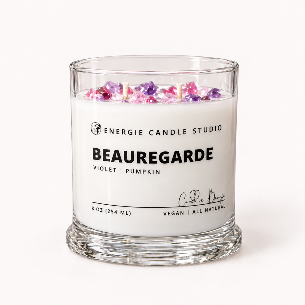 A 8 oz glass jar candle by Energie Candle Studio, scented 'Beauregarde' (Violet | Pumpkin), featuring white wax topped with pink and purple flower petals, in a clear glass container on a white background.