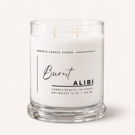 A two-wick scented candle in a clear glass jar with white wax, featuring a white label with black text that reads 'Burnt ALIBI' and 'ENERGIE CANDLE STUDIO'.