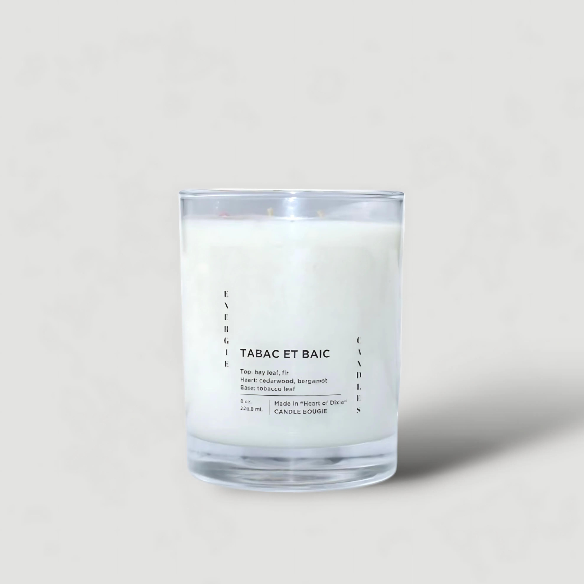 White candle with a cotton wick, placed on a plain peach table and a plain peach background.