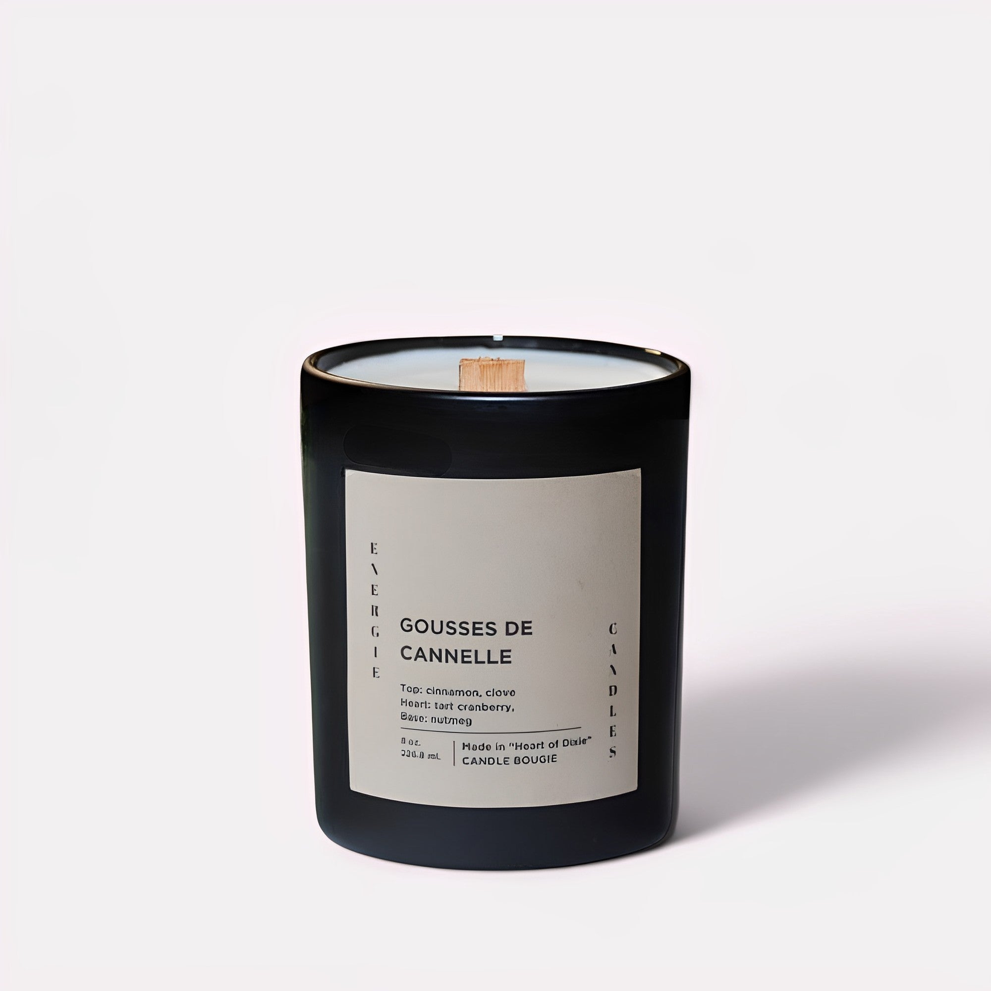 A black candle with white wax and a wooden wick, set against a grayish backdrop, exuding a minimalist and modern aesthetic.