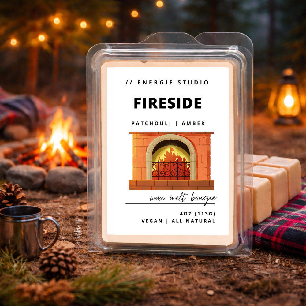 Wax melt package labeled 'Fireside' by Energie Studio with a fireplace illustration, set against a cozy campfire background.