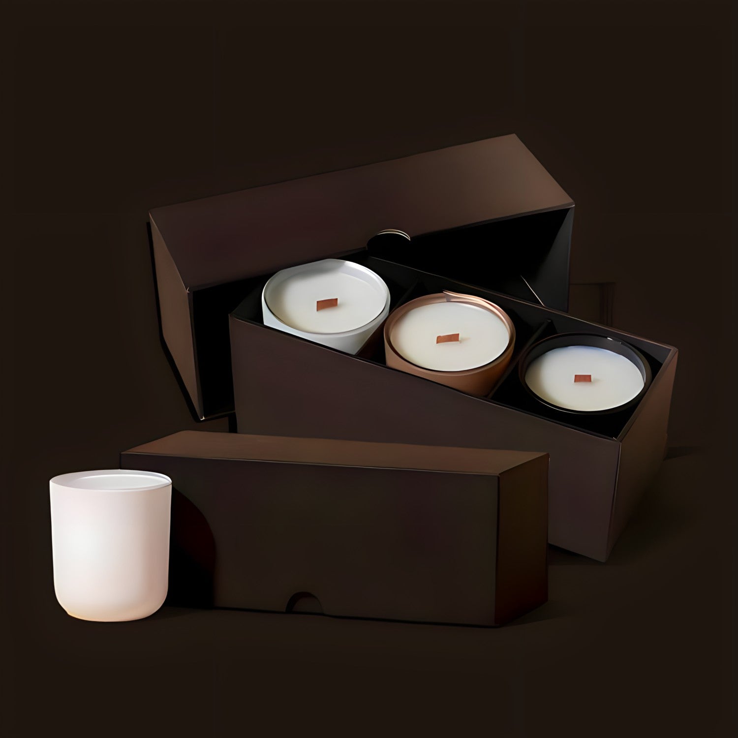 Premium brown luxury box containing three candles with wood wicks, each encased in white, chrome, and metallic silver vessels