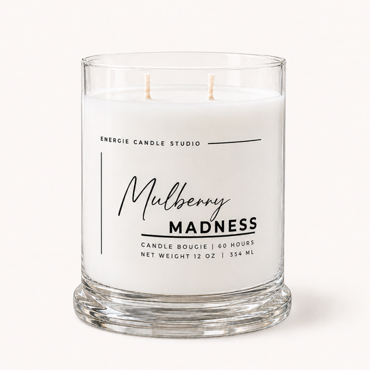 A two-wick scented candle in a clear glass jar with white wax, featuring a white label with black text that reads 'Mulberry MADNESS' and 'ENERGIE CANDLE STUDIO'.