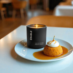 A Mousse and Maple candle sitting on a white plate with a dallop of pumpkin mousse and whipped cream 