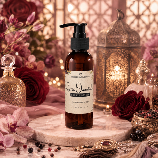 A bottle of Erica Orientale Rosemary Hair Growth serum stands on a round stone plinth in a styled setting with roses, lanterns, and decorative accessories. The product is in an amber glass bottle with a black pump and a cream label.