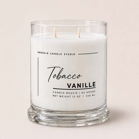 A two-wick scented candle in a clear glass jar with white wax, labeled 'Tobacco Vanille' by Energie Candle Studio, set against a solid light beige background.
