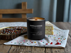 Vanilla Kisses candle on a wooden table with a cake and decorative elements.