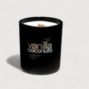 A black candle with white wax and a wooden wick, set against a taupe backdrop, exuding a minimalist and modern aesthetic.