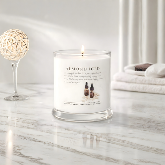 Candle labeled 'Almond Iced' on a marble surface with decorative elements.