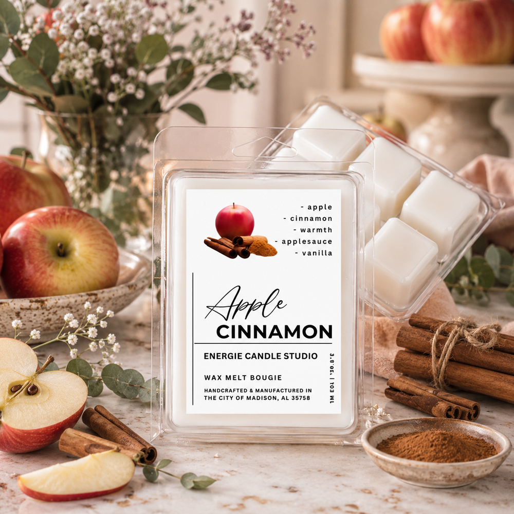 A clear plastic clamshell package of Energize Candle Studio 'Apple Cinnamon' wax melt bougies, displayed on a rustic marble surface surrounded by apples, cinnamon sticks, and flowers.
