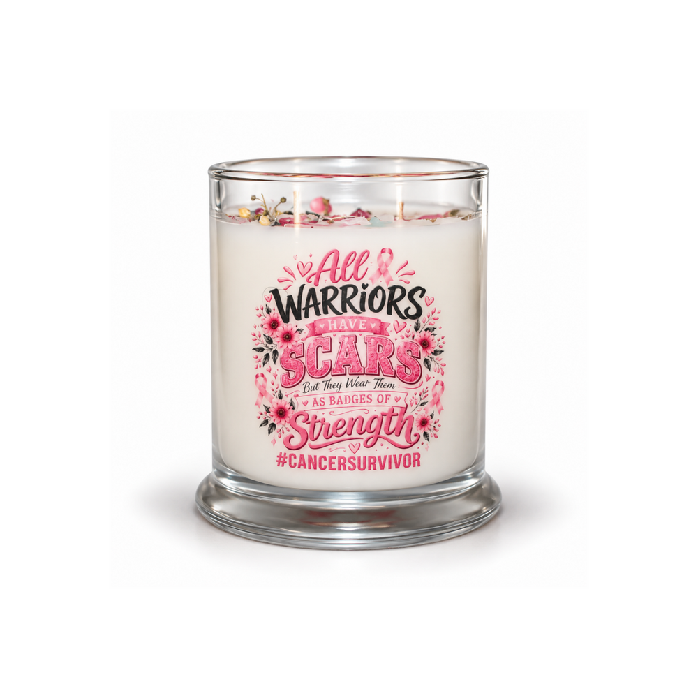 A glass jar candle with white wax and a clear glass base, featuring a printed front label with pink and black text reading 'All Warriors Love My Scars' and '#Cancersurvivor,' decorated with pink flowers and a ribbon. The candle is lit with two visible flames against a clean white background.