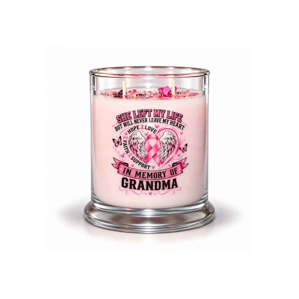 A pink memorial candle in a clear glass jar with a glass base, featuring a printed graphic with a pink ribbon, heart, and the text 'SHE LEFT MY LIFE BUT WILL NEVER LEAVE MY HEART.
