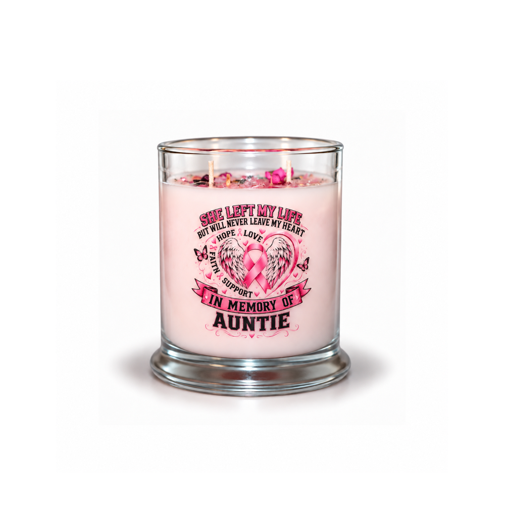 A pink scented candle in a clear glass jar with a printed memorial design on the front. The candle has two lit wicks and pink flower petals floating on the surface.