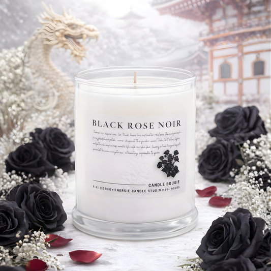 Candle labeled 'Black Rose Noir' surrounded by black roses and white flowers with a blurred background