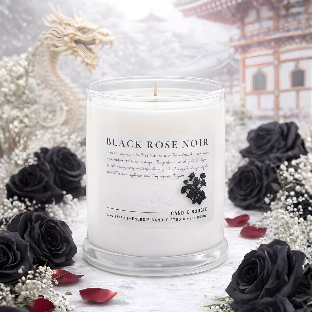 Candle labeled 'Black Rose Noir' surrounded by black roses and white flowers with a blurred background