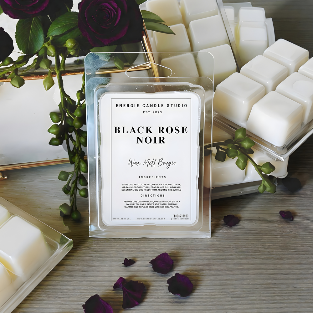 Energie Candle Studio Black Rose Noir wax melt packaging with purple roses and greenery on a wooden surface.