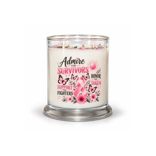 A glass jar candle with a clear glass body and base, filled with creamy off-white wax. The front features a printed graphic with the words 'Admire the Survivors Honor the Taken Support the Fighters' in black and pink lettering, surrounded by pink ribbons, butterflies, and flowers.