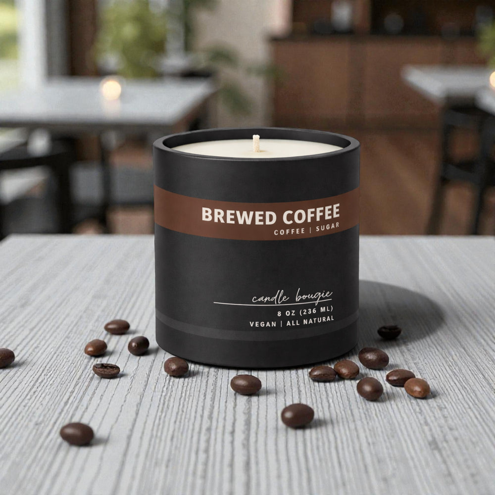 Brewed coffee-scented candle on a table with scattered coffee beans