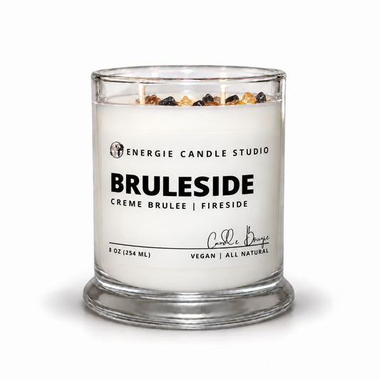 An 8 oz glass jar candle by Energie Candle Studio, featuring a white wax fill, three wicks, and decorative amber and black stones on top, with a white label reading 'BRULESIDE'.