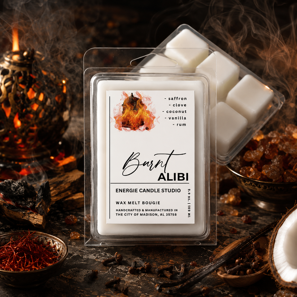 A wax melt bougie in a clear clamshell package labeled 'Burn ALIBI' by Energie Candle Studio, surrounded by warm decorative props including a candle, bowls of spices, and coals on a dark rustic surface.