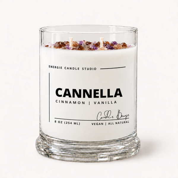 A 9 oz glass jar candle by Energie Candle Studio named 'Cannella' with 'Cinnamon | Vanilla' on the label. The candle features white wax topped with dried cinnamon and vanilla botanicals, housed in a clear glass container with two wicks, set against a clean white background.