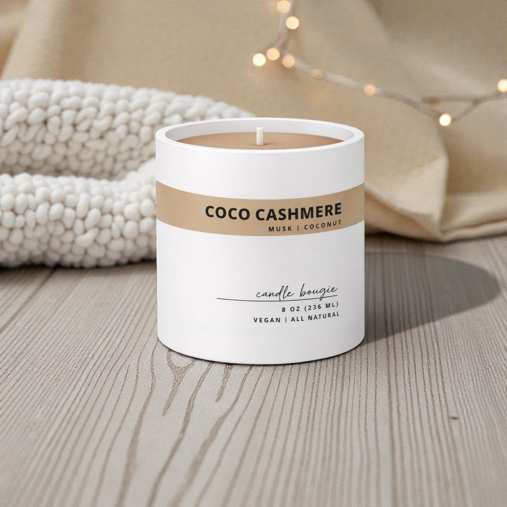 Candle labeled 'Coco Cashmere' on a wooden surface with soft lighting