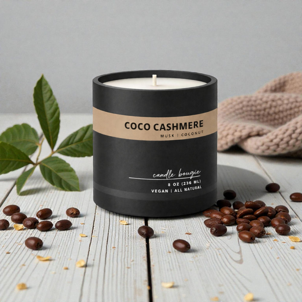 Candle labeled 'Coco Cashmere' with coffee beans and leaves on a wooden surface