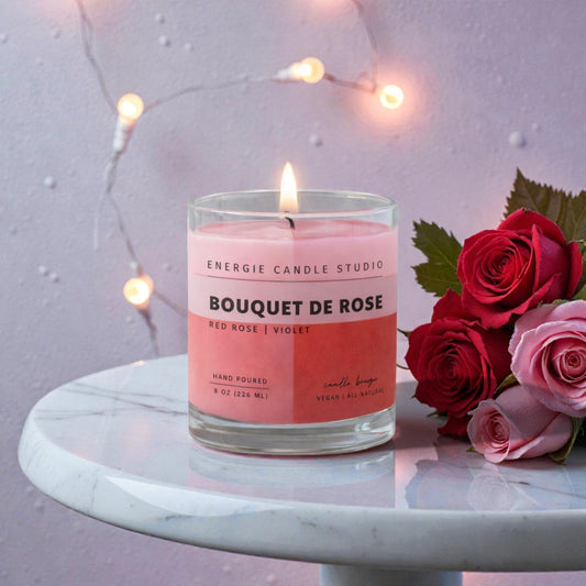 Pink candle labeled 'Bouquet de Rose' with red and pink roses on a marble surface.