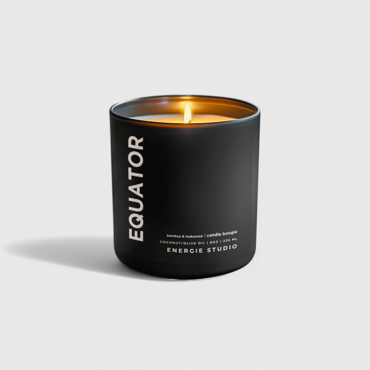A black candle with a linen color background with a cotton wick and a orange flame