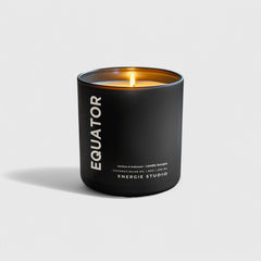 A black candle with a linen color background with a cotton wick and a orange flame