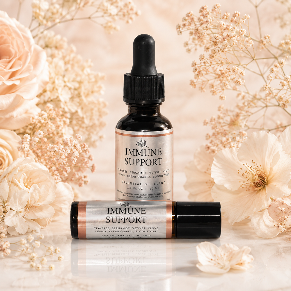 A small amber dropper bottle and matching tube labeled IMMUNE SUPPORT, arranged on a light marble surface with soft cream flowers and dried botanicals around them.