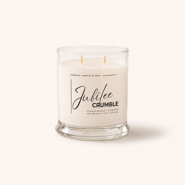 A double-wick candle in a clear glass jar with white wax, labeled 'Jubilee CRUMBLE' by Energy Candle Studio, set against a solid off-white background.