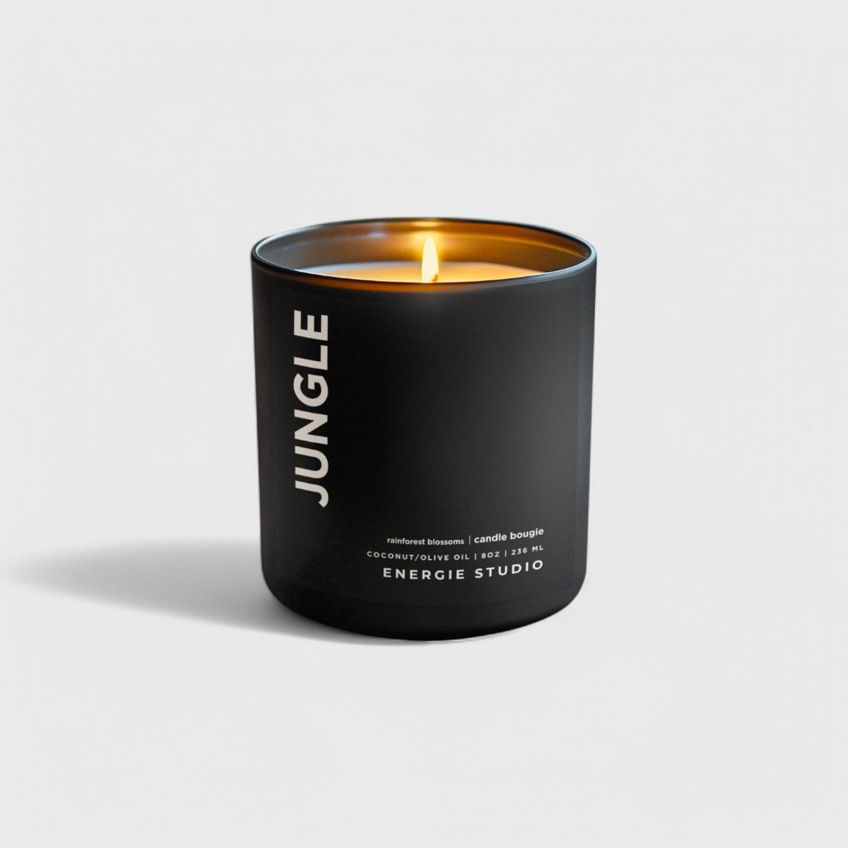 a black candle with a cotton wick and orange glow set in a white background