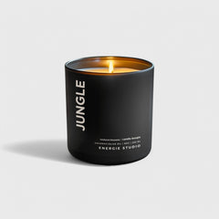 a black candle with a cotton wick and orange glow set in a white background