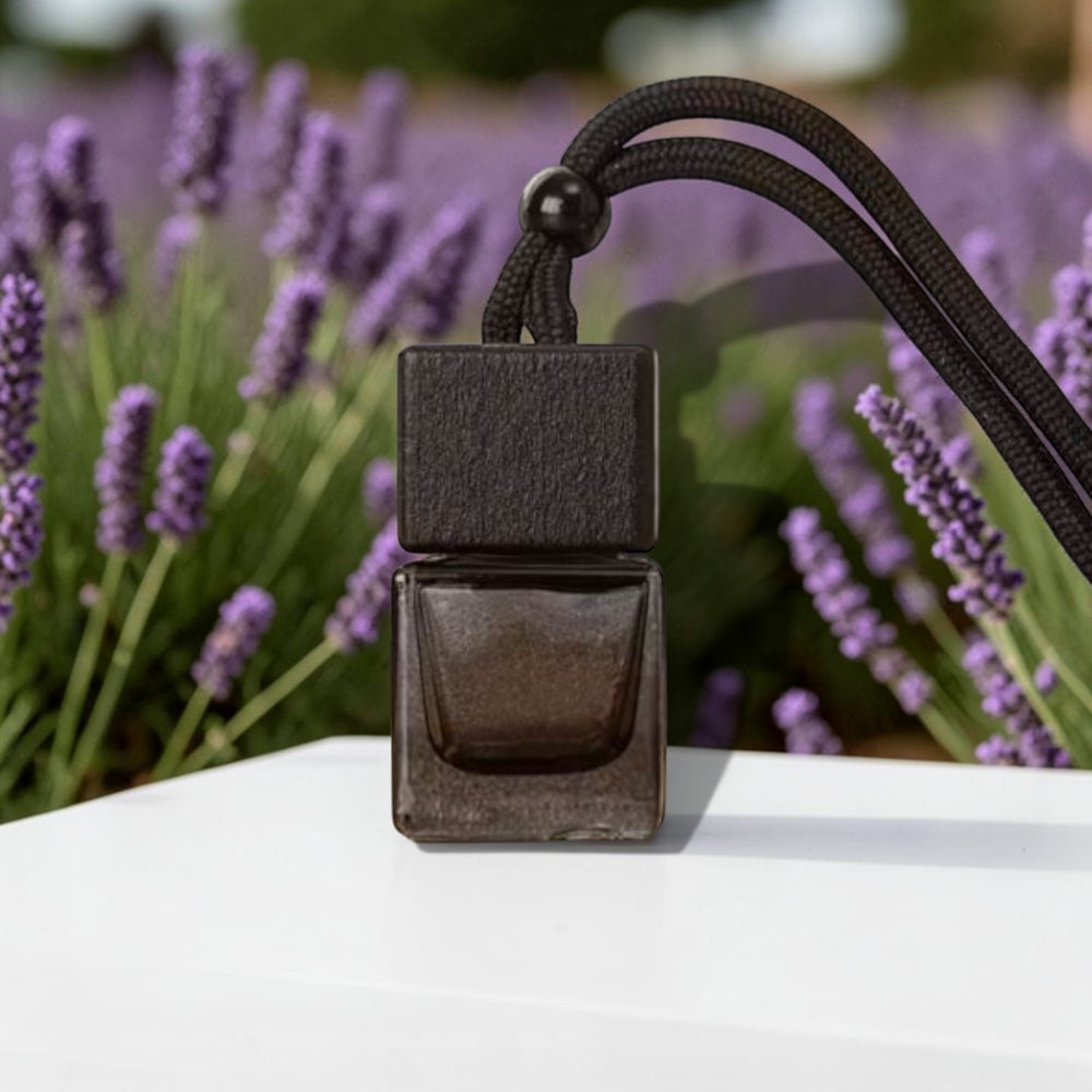 Small dark-colored perfume bottle with a black strap against a blurred lavender background