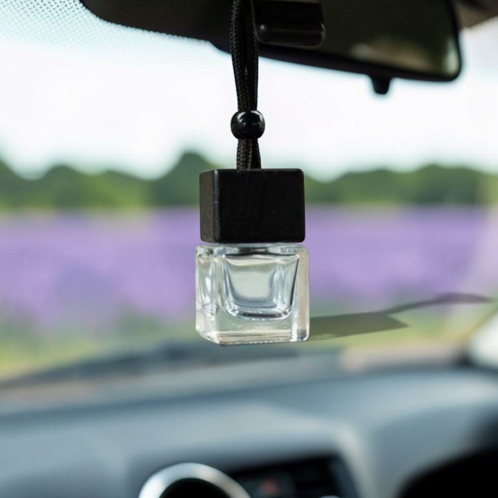 Car air freshener hanging from a car's rearview mirror with a blurred lavender field in the background