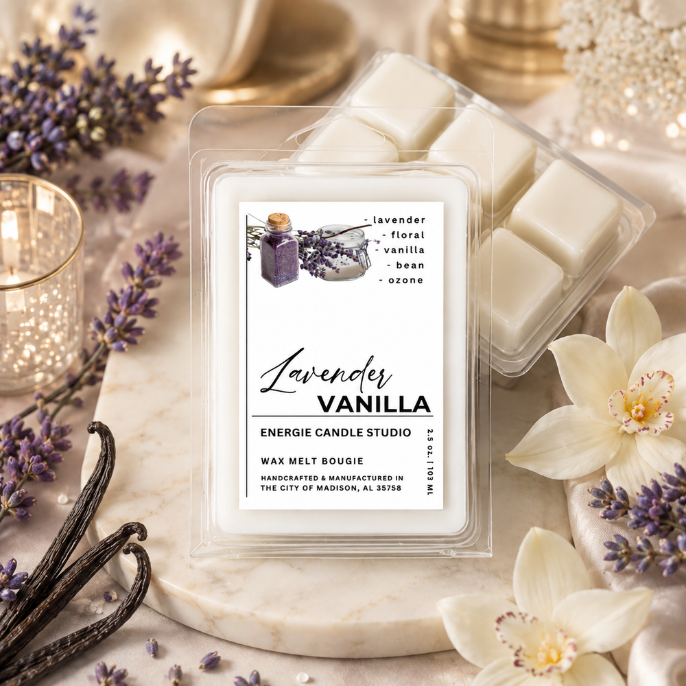 A clear plastic clamshell package of Energize Candle Studio 'Lavender Vanilla' wax melts sits on a white marble slab, surrounded by lavender flowers, vanilla beans, and a lit candle in a gold-toned holder.