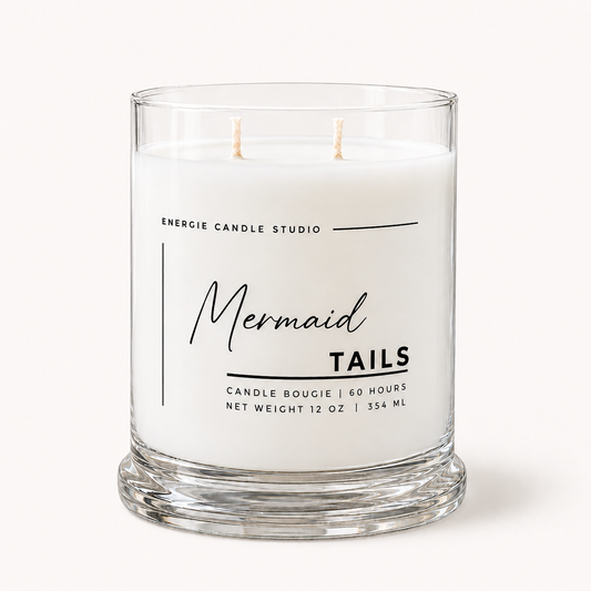 A two-wick glass jar candle with white wax and a clear glass base, featuring a white label with black text that reads 'Mermaid Tails' and 'ENERGIE CANDLE STUDIO'.