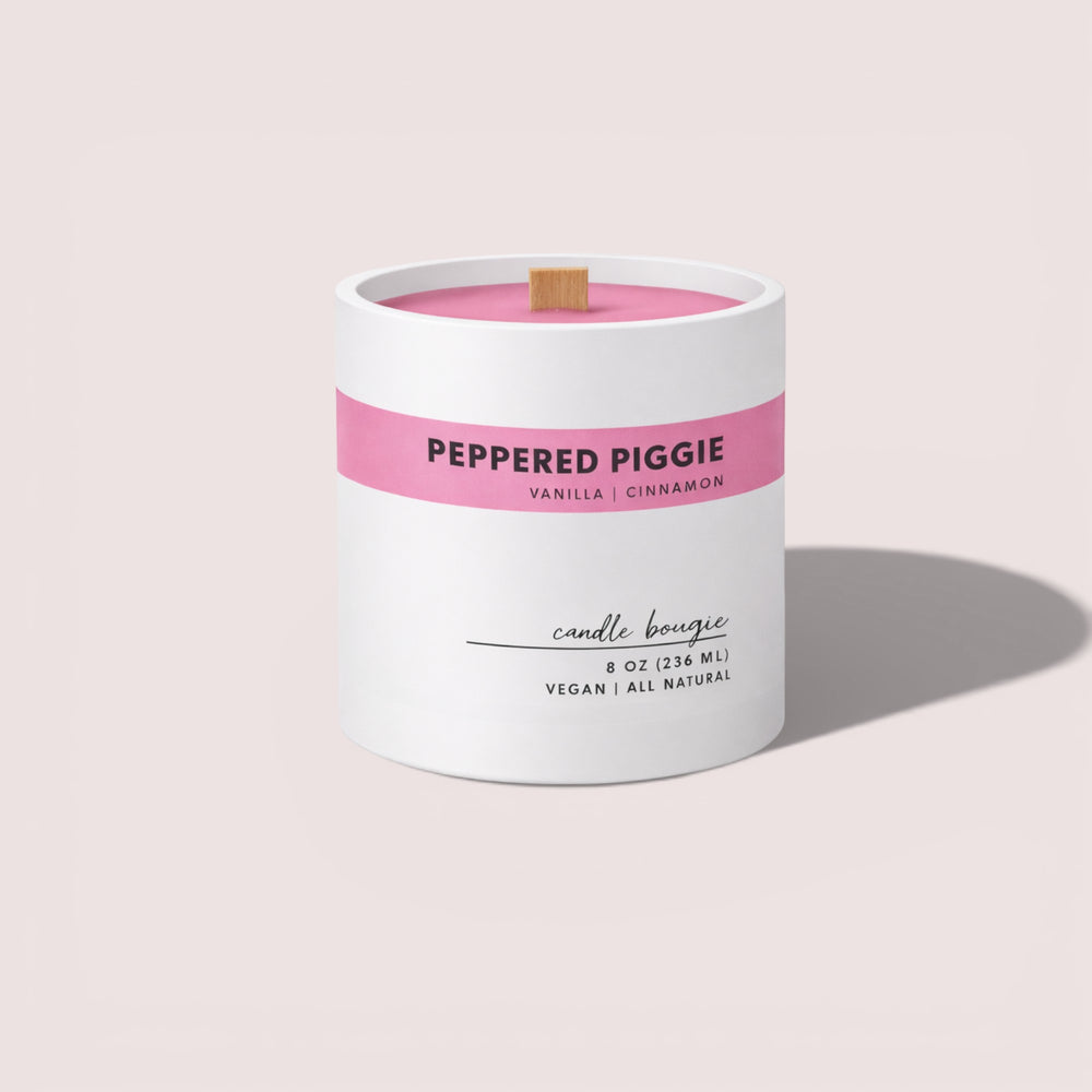 Candle with 'Peppered Piggie' label on a light pink background