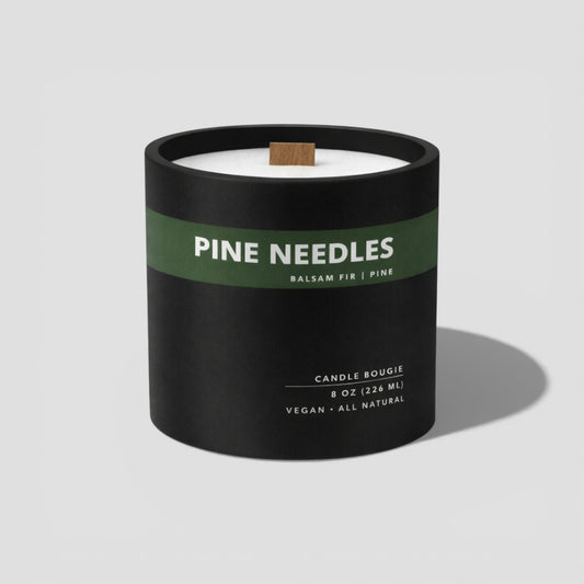 Candle with 'Pine Needles' label on a light gray background