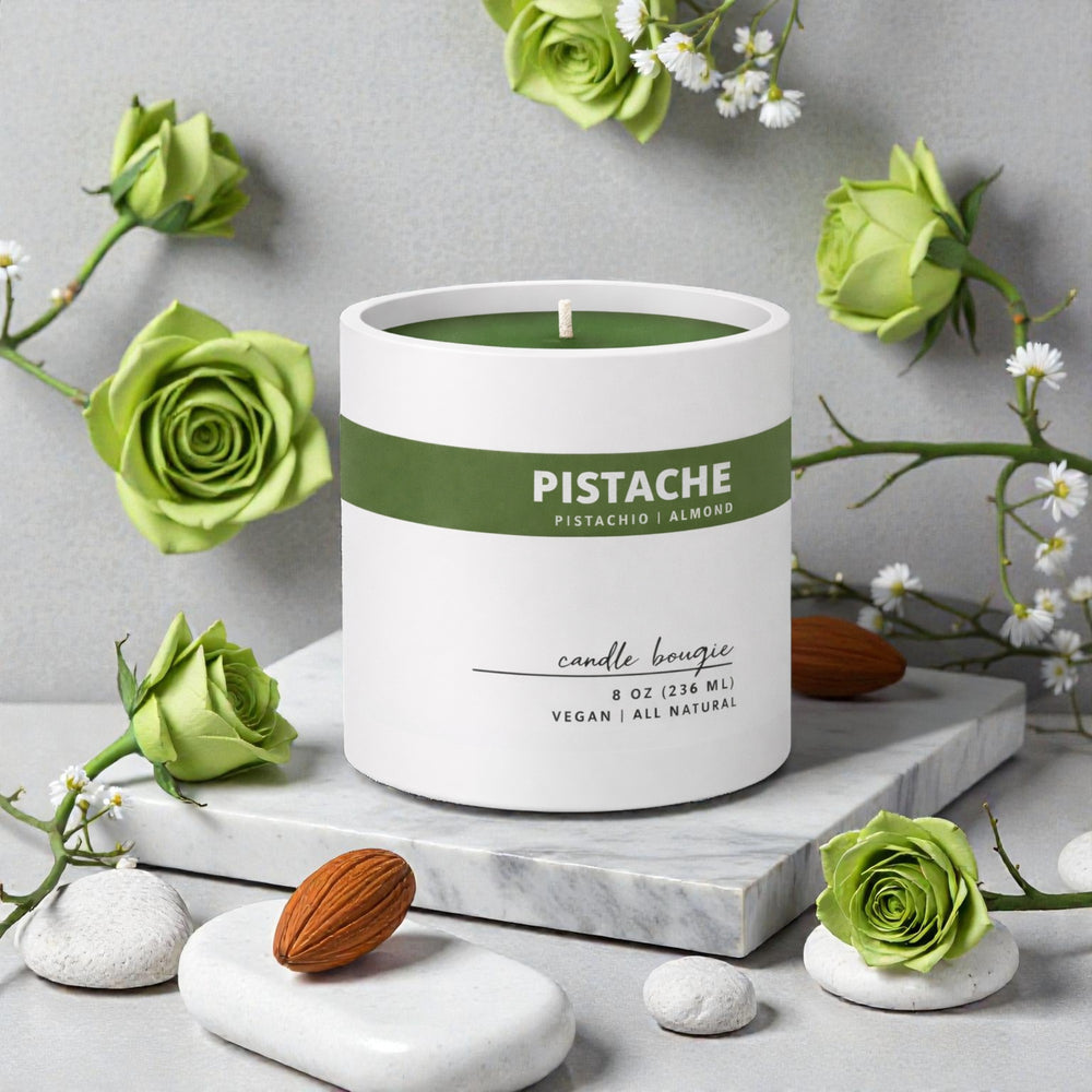 Pistachio candle with green label surrounded by green roses on a gray background