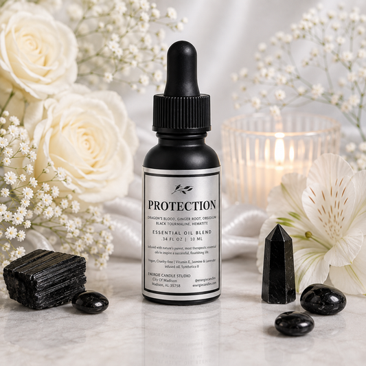 A bottle of Protection Sacred Black Candle Studio Essential Oil Blend essential oil blend, styled on a marble surface with white roses, crystals, and a lit candle in the background.