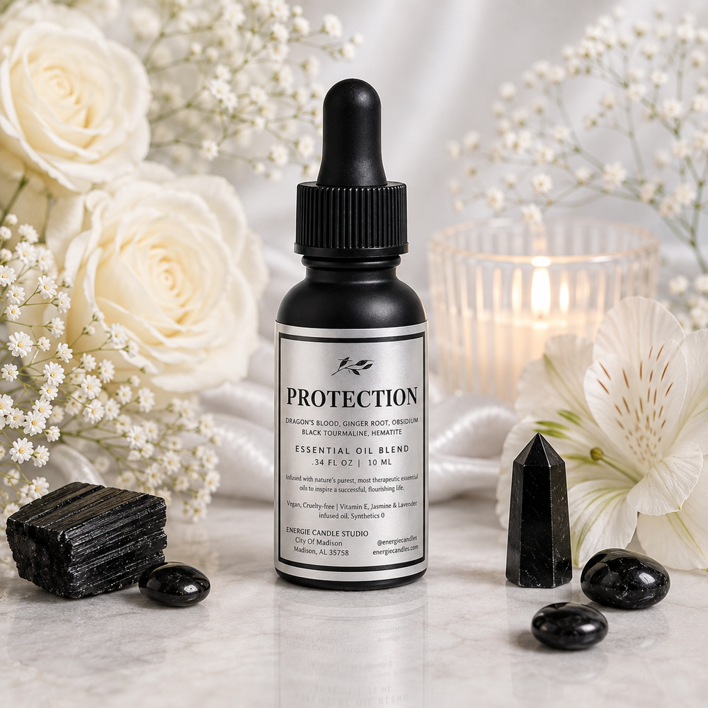 A bottle of Protection Sacred Black Candle Studio Essential Oil Blend essential oil blend, styled on a marble surface with white roses, crystals, and a lit candle in the background.
