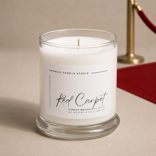 Candle in a glass jar labeled 'Red Carpet' from Energie Candle Studio on a neutral background.